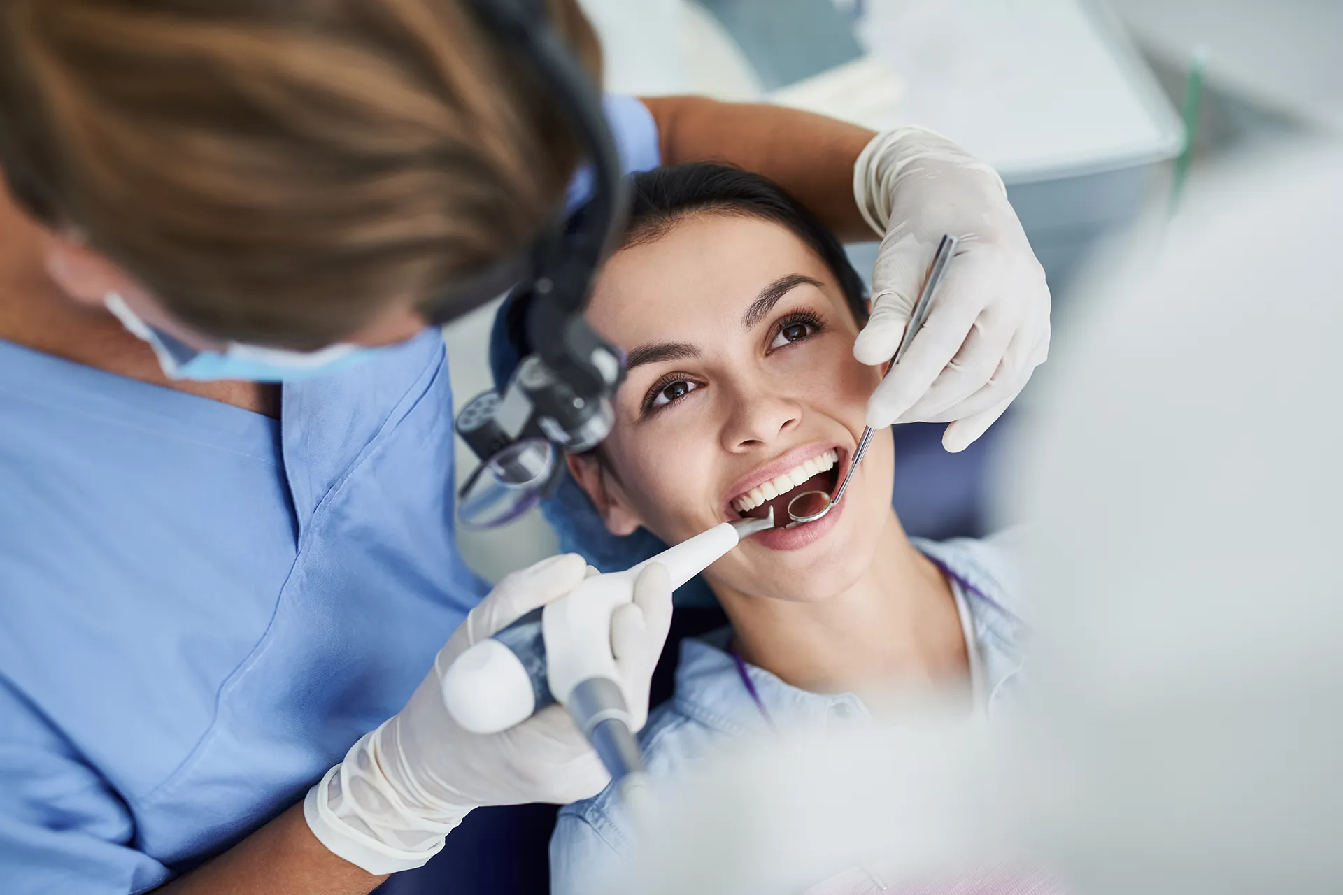 Dentist performing a dental examination on a smiling young woman.