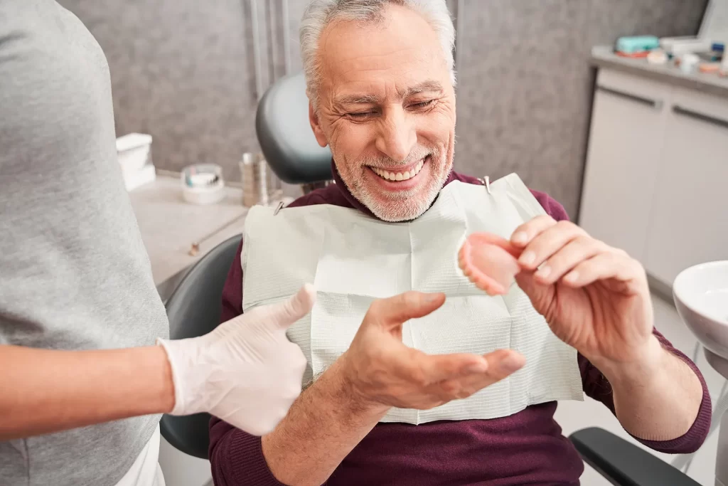 Dentist showing senior patient teeth denture.