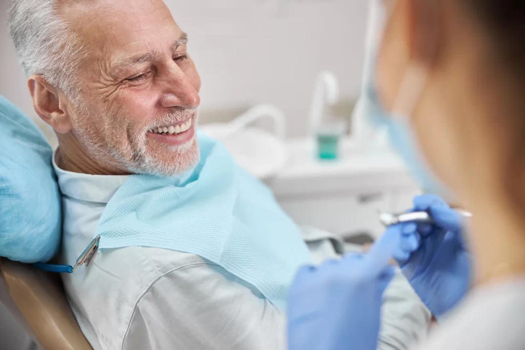 Senior man smiling during a dental consultation with a dentist.