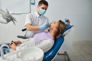 A male dentist conducts a thorough dental examination of a female patient’s teeth in a professional clinical setting.