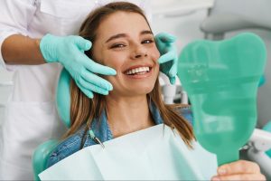 Happy female patient in an exam chair looking into a mirror.