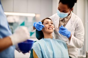 A woman smiles during a dentist teeth cleaning procedure.