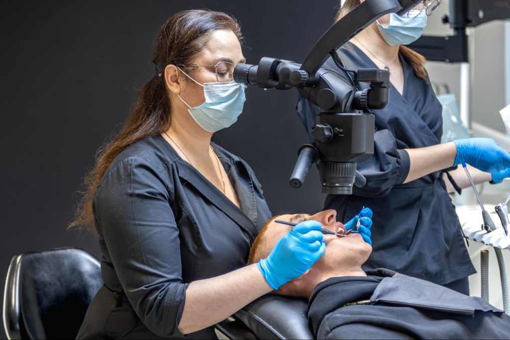 Dentist performing teeth cleaning with a modern dental device.