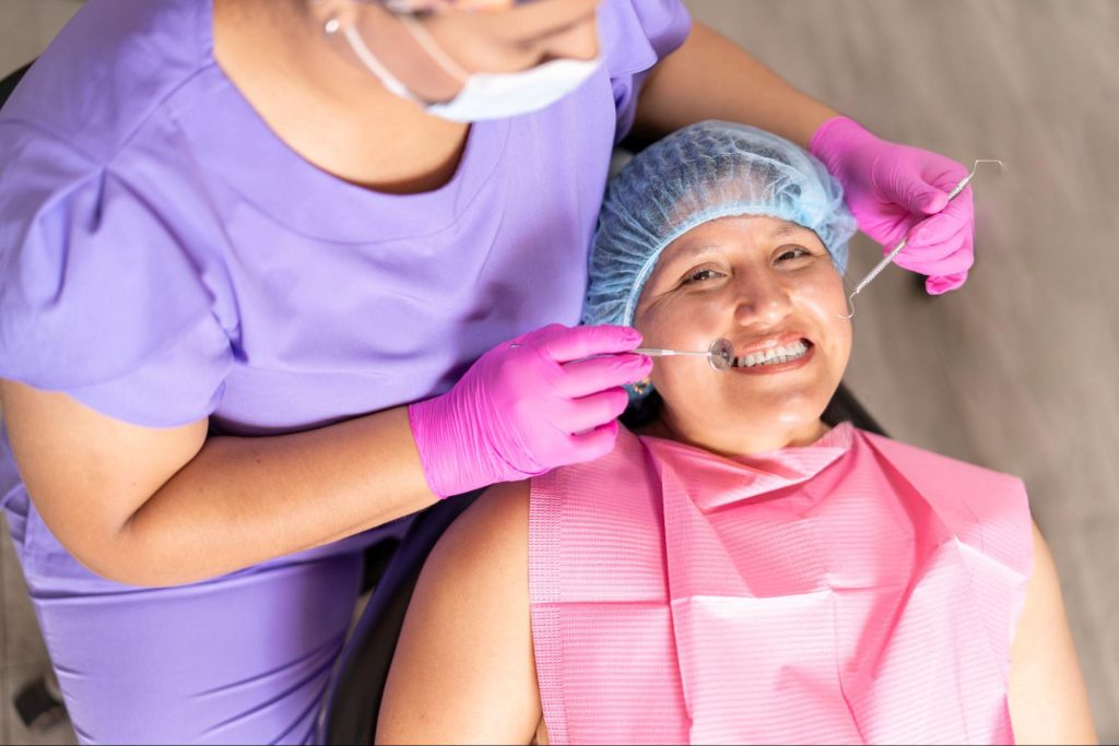 A smiling patient sits with the dentist during a routine oral health check.