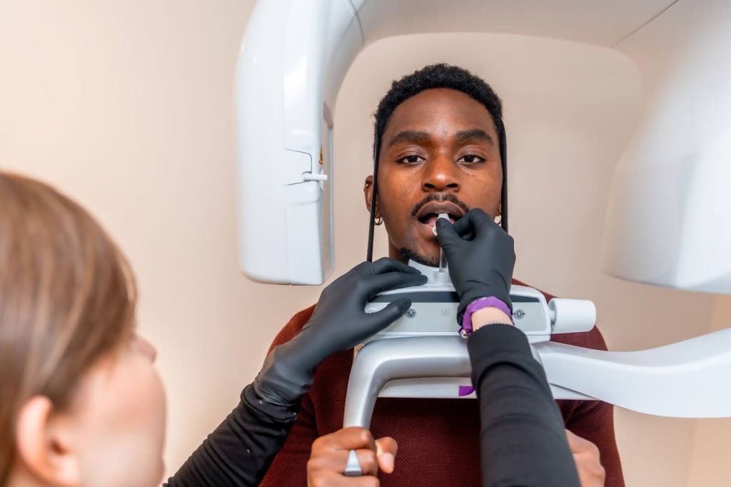 A dentist prepares a young man for a dental X-ray.